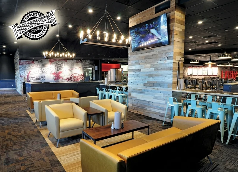 Fuddruckers restaurant interior with layered pendant lighting, upholstered lounge seating and timber finishes
