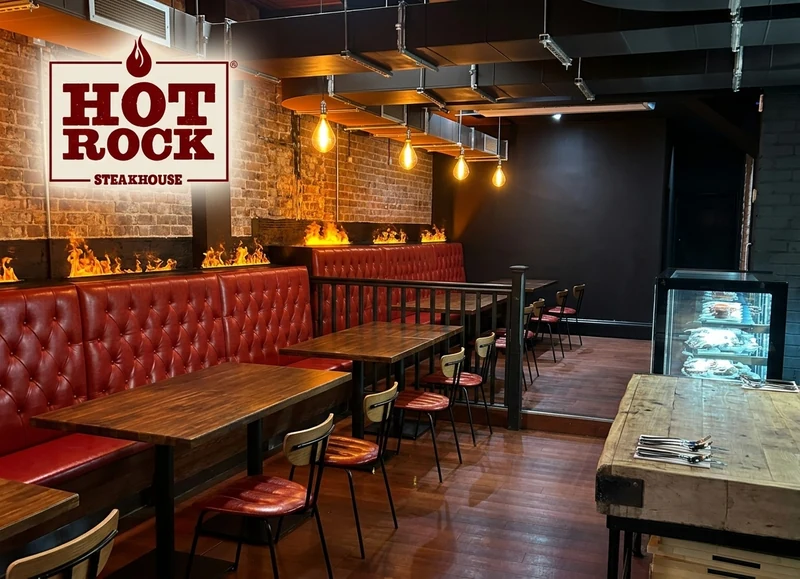 Hot Rock Steakhouse dining room with brick wall, deep red booths and dark timber tables