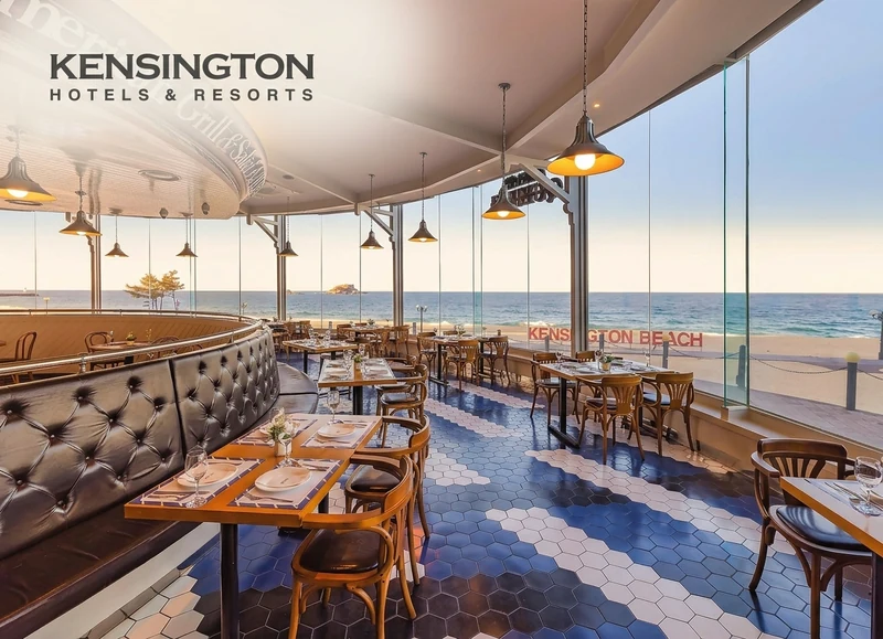 The Kensington beachfront dining interior with upholstered booths, warm pendant lighting and ocean views