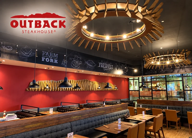 Outback Steakhouse restaurant with warm timber booths, red feature walls and statement pendant lighting