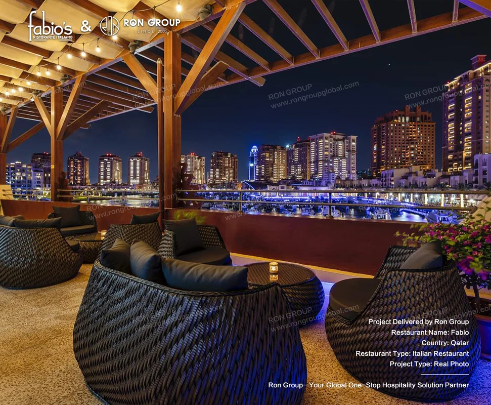 Fabio rooftop lounge with wicker seating string lights city skyline and waterfront night view