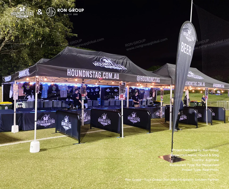 Hound Stag outdoor event tent setup with branded black tents string lights and beer flag
