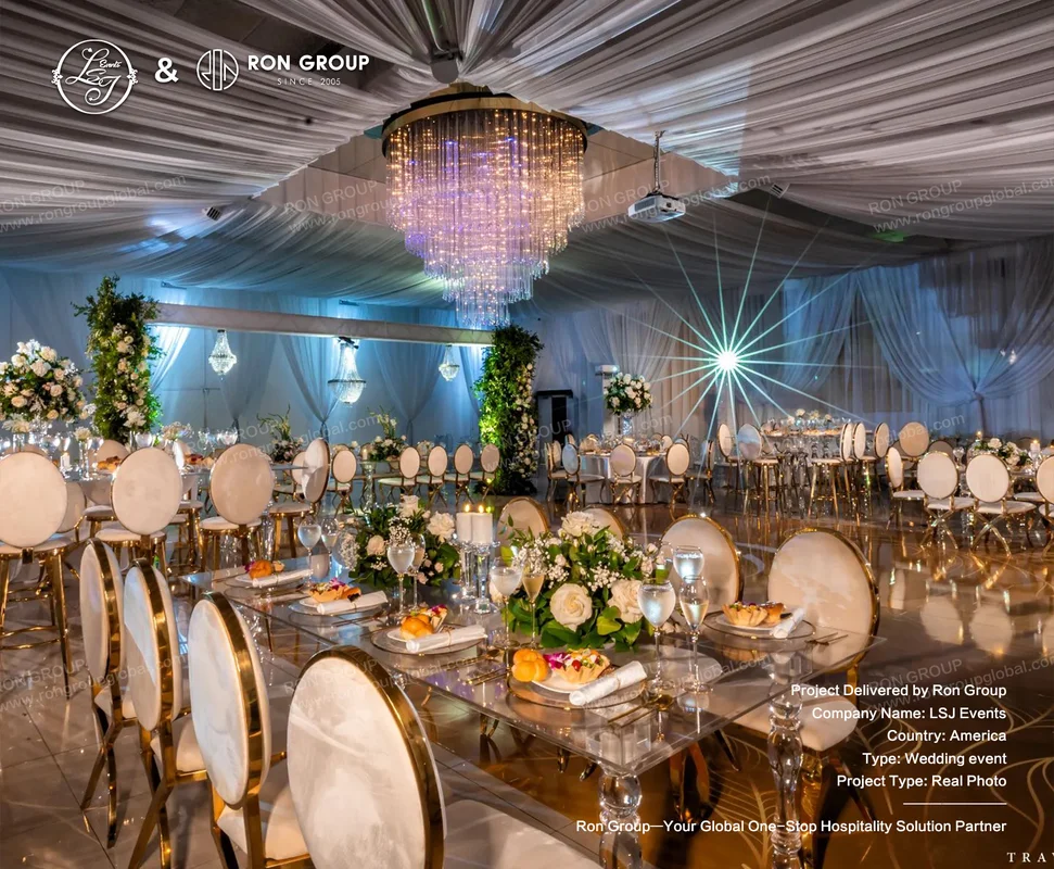 Elegant wedding reception hall with glass tables, floral centerpieces, gold chairs, and chandelier lighting for LSJ Events