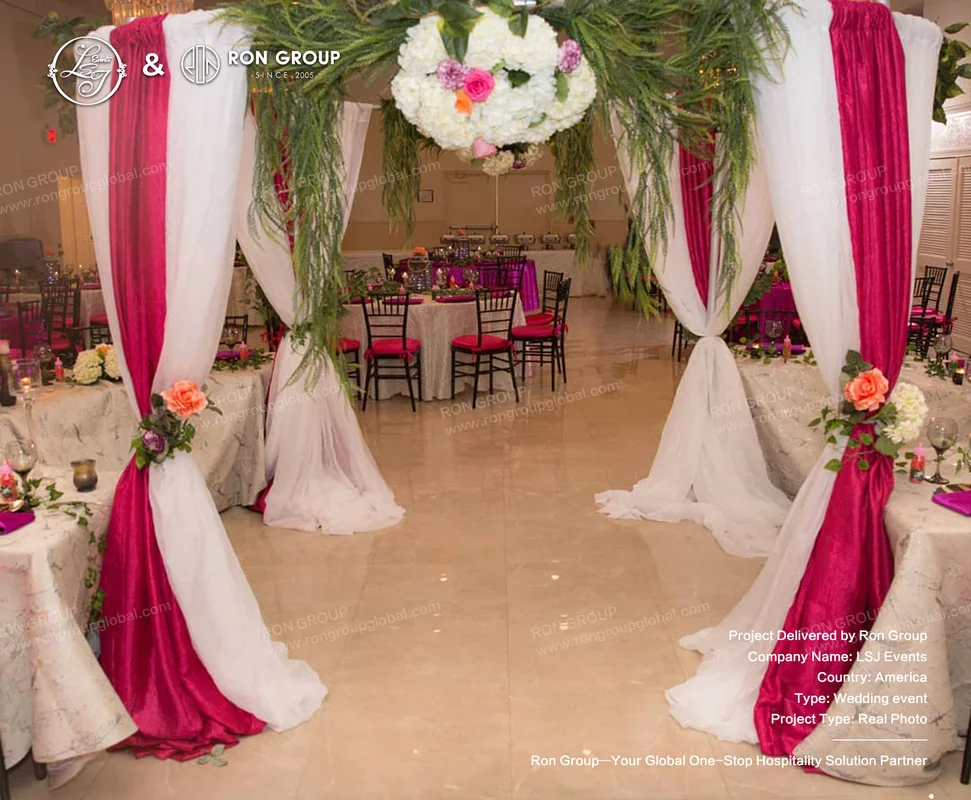 Wedding reception entrance arch with pink and white floral decor and draped fabric