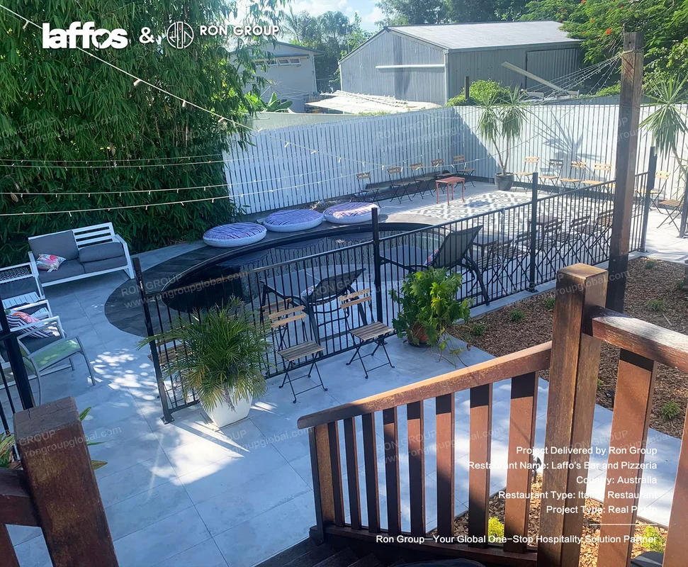 Laffos Bar and Pizzeria outdoor restaurant patio with black railings wooden chairs round seating plants and string lights