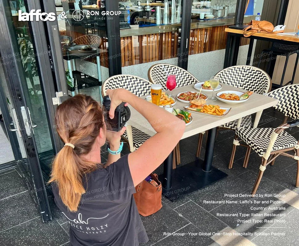 Laffos Bar and Pizzeria customer photographing Italian dishes and drinks at outdoor table
