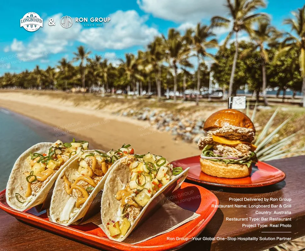 Longboard Bar & Grill RonGroup-Longboard_Bar_Grill-Tacos_And_Burger_On_Beach_Table.webp