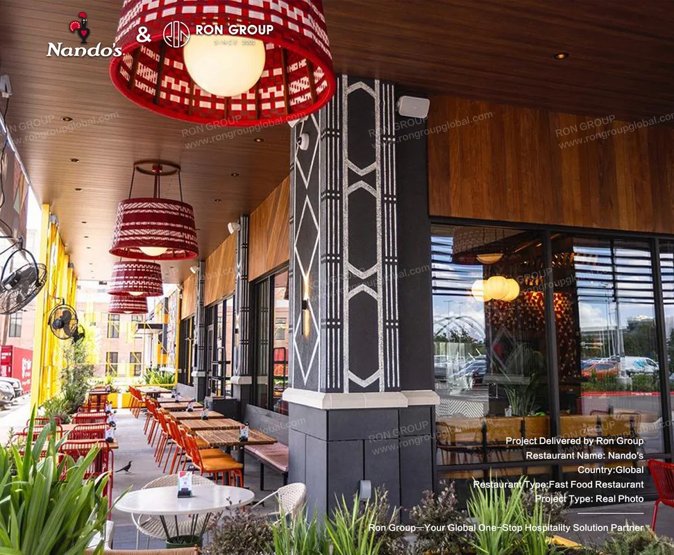 Nando's outdoor restaurant seating area with orange chairs and red pendant lights