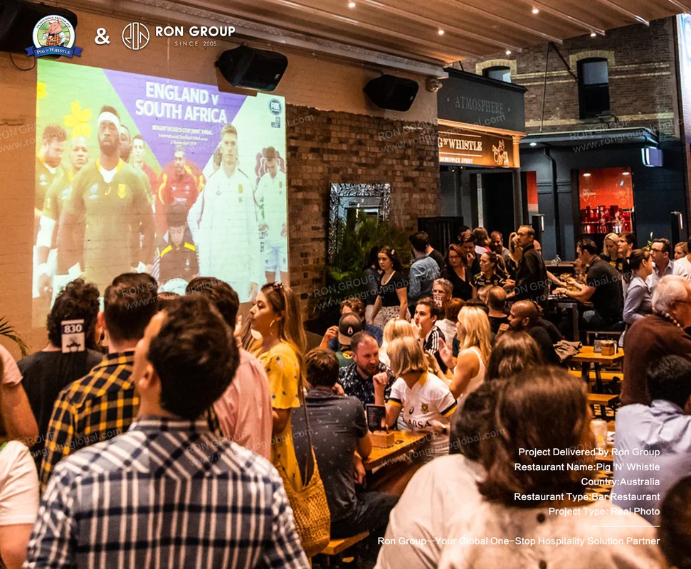 Lively bar interior with patrons watching rugby on big screen
