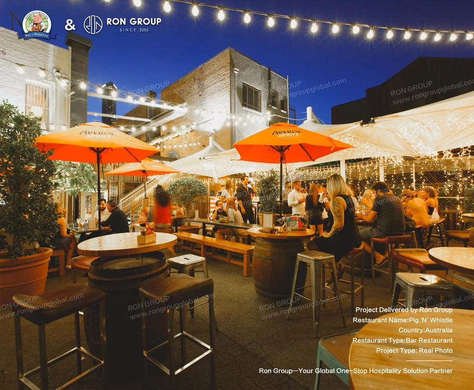 Outdoor patio at dusk with string lights and Aperol umbrellas