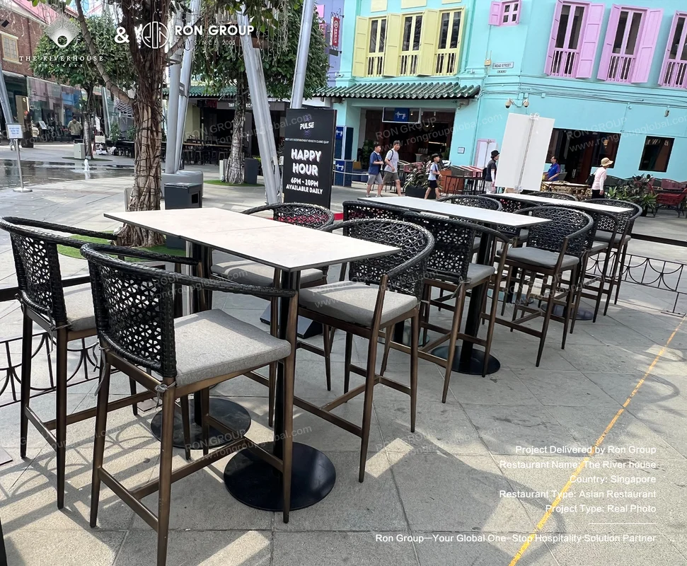 Riverhouse modern outdoor bar tables and woven cushioned chairs against colorful colonial buildings
