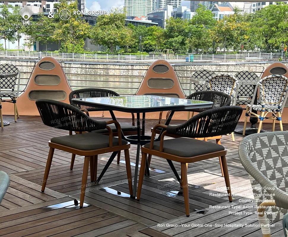 Riverhouse outdoor dining area by Singapore River with woven chairs glass table deck and city skyline