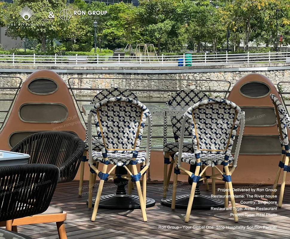 Riverhouse outdoor dining chairs by river with blue white woven pattern wooden frames and swivel bases