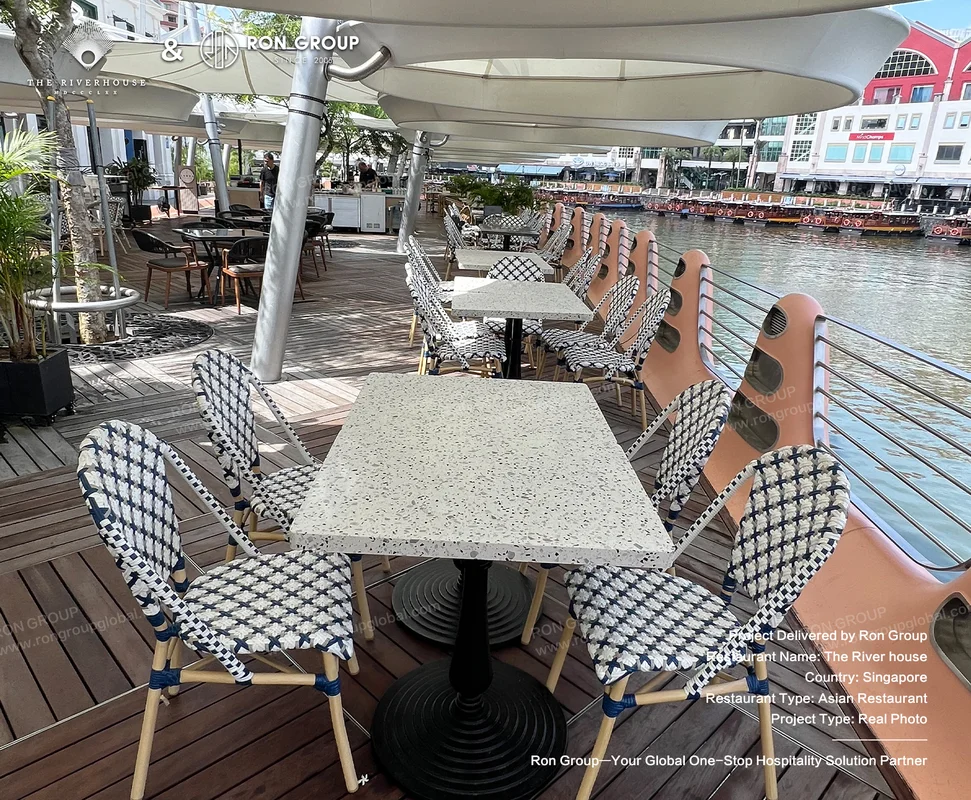 Riverhouse outdoor riverside dining area with terrazzo tables woven chairs umbrellas and boats