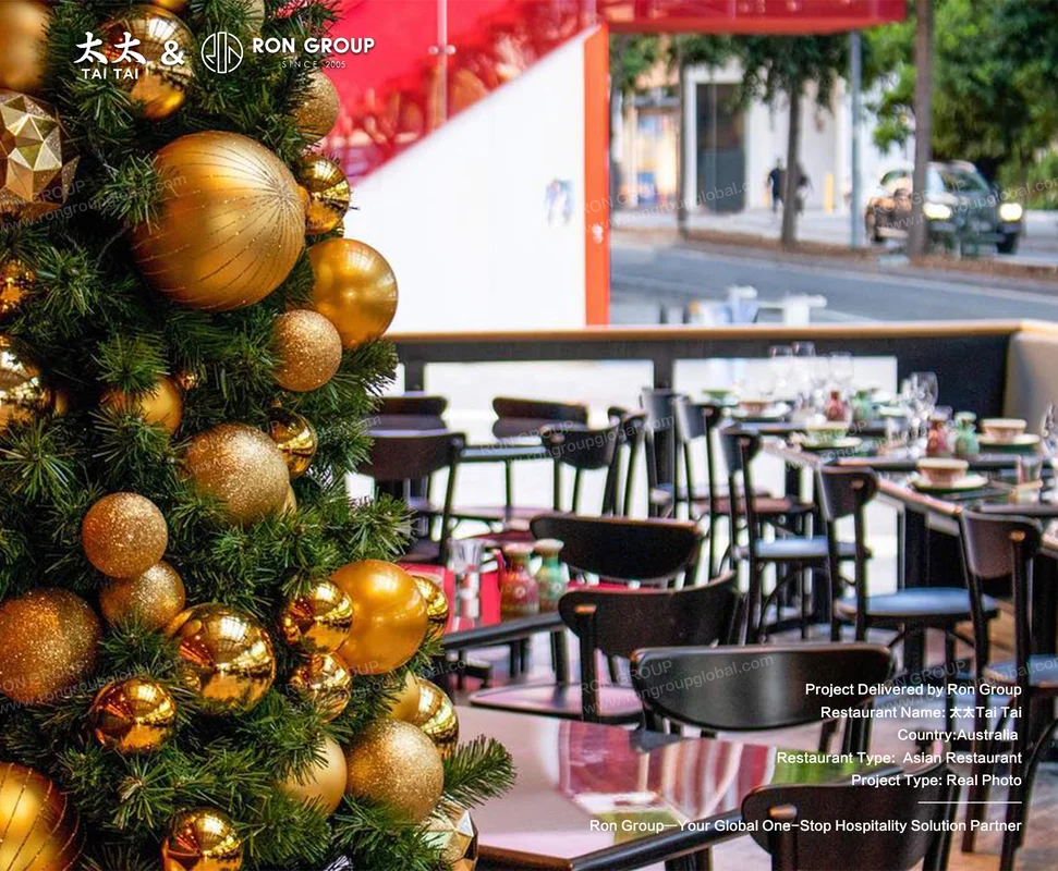 Christmas tree beside outdoor dining with red facade