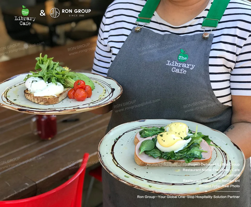 The Library Cafe server holding two plates of avocado toast