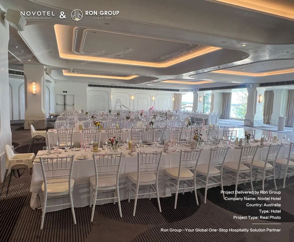 Hotel banquet hall with white event chairs and long dining tables