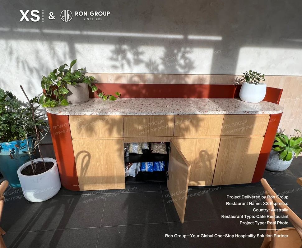 Cafe counter with terrazzo top wood drawers red accents and plants