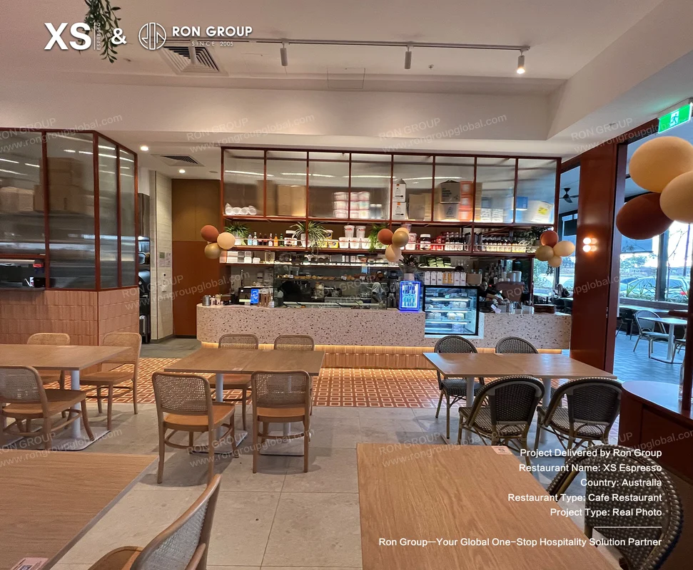 Wooden cafe tables and woven chairs near display counter
