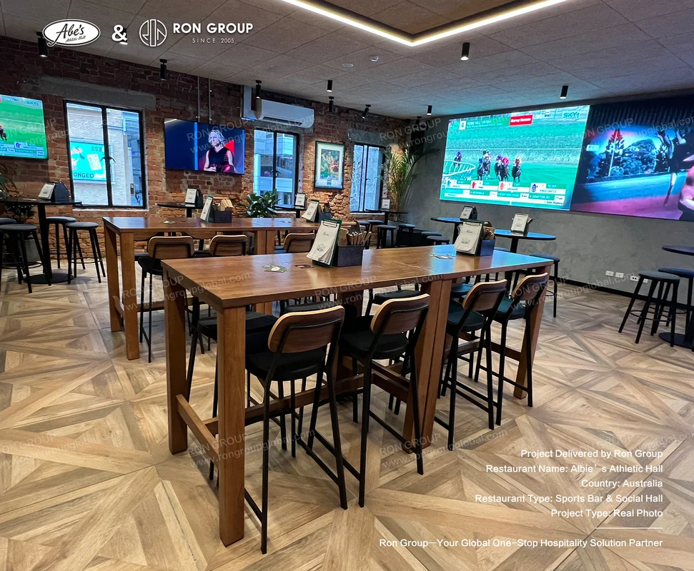 Main sports viewing hall with herringbone wood floors timber tables black chairs and brick walls