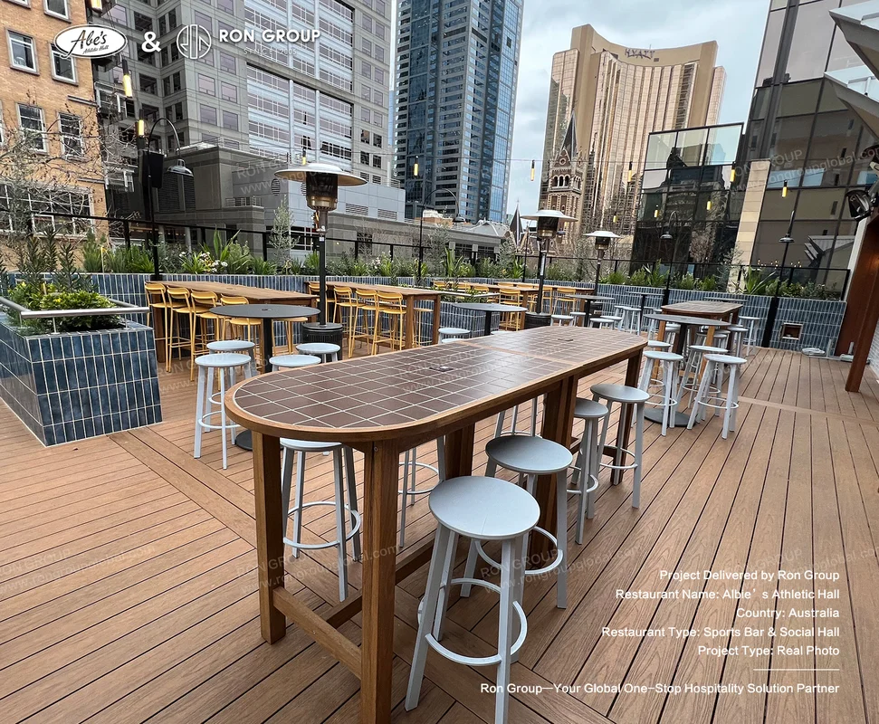 Rooftop outdoor dining zone with timber tables metal stools overhead heaters and string lights