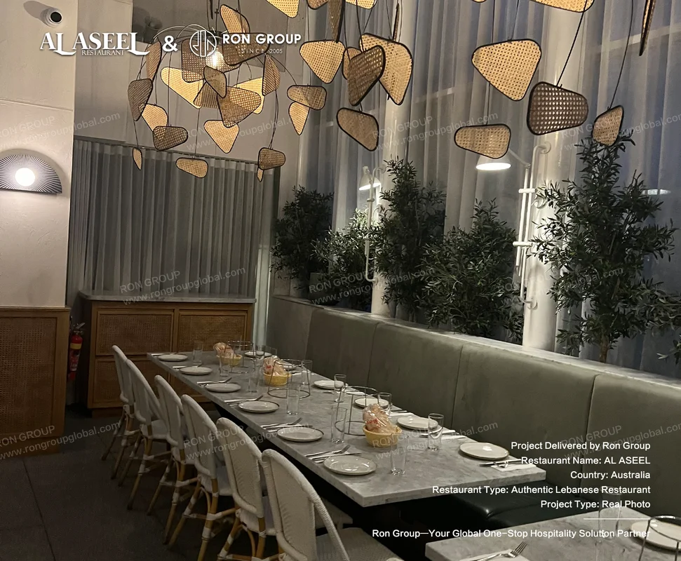 Long white marble dining table with white wicker chairs and woven pendant lights at Al Aseel
