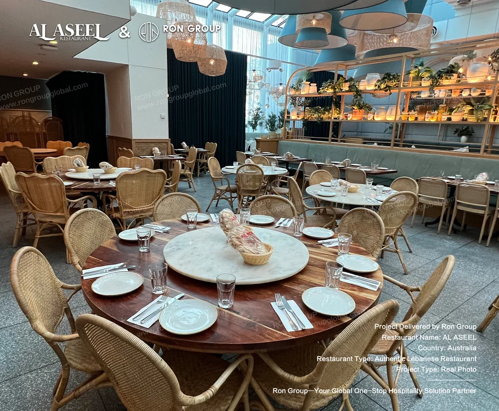 Round wooden dining tables with marble lazy susans and rattan chairs at Al Aseel