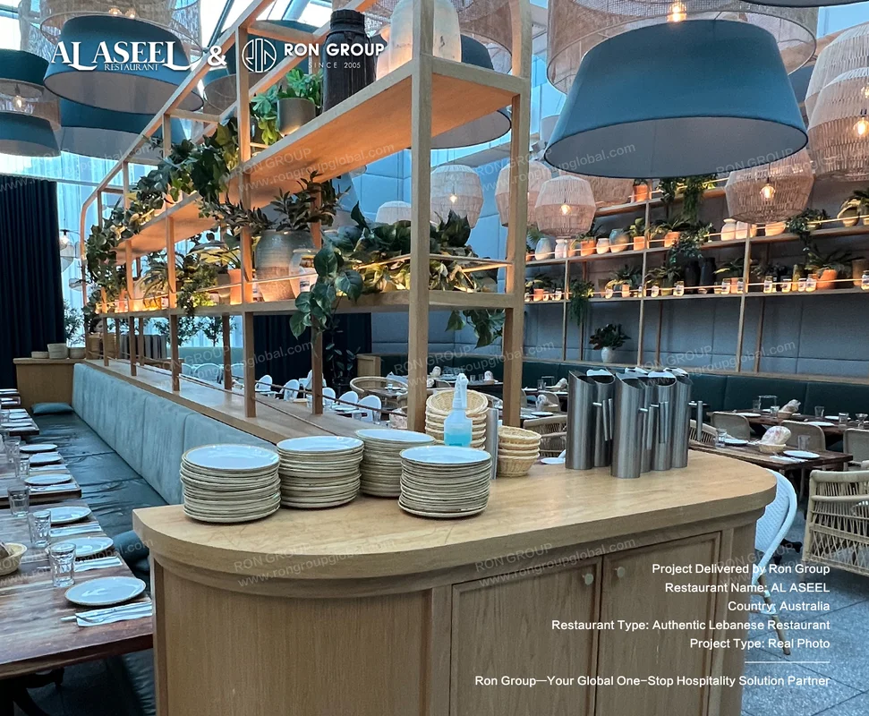 Central waiter service station with stacked plates carafes and greenery shelving at Al Aseel
