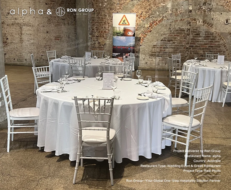 Alpha wedding banquet setup with white linen round tables and silver chiavari chairs