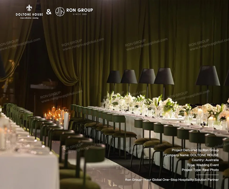 Long wedding banquet table with olive drapery dark green chairs and black table lamps