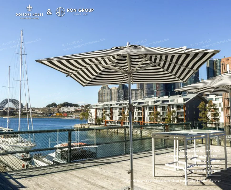 Black and white striped commercial patio umbrella on Doltone House harbourside timber deck