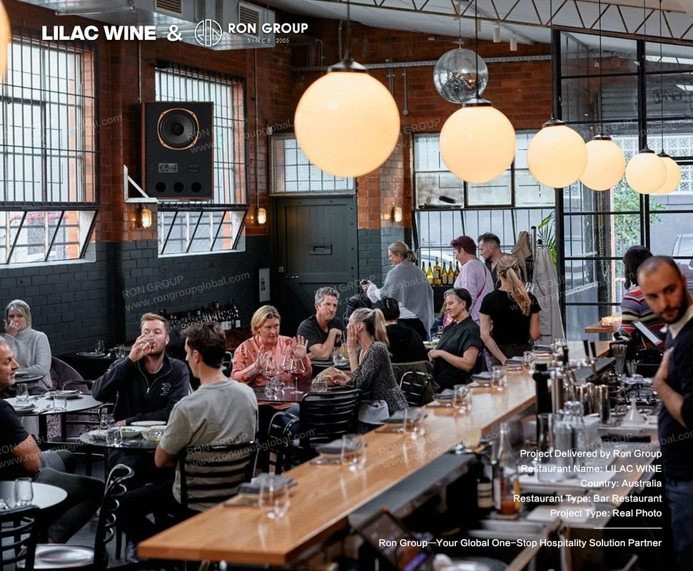 Long wooden wine bar and exposed brick dining room with globe pendants at Lilac Wine