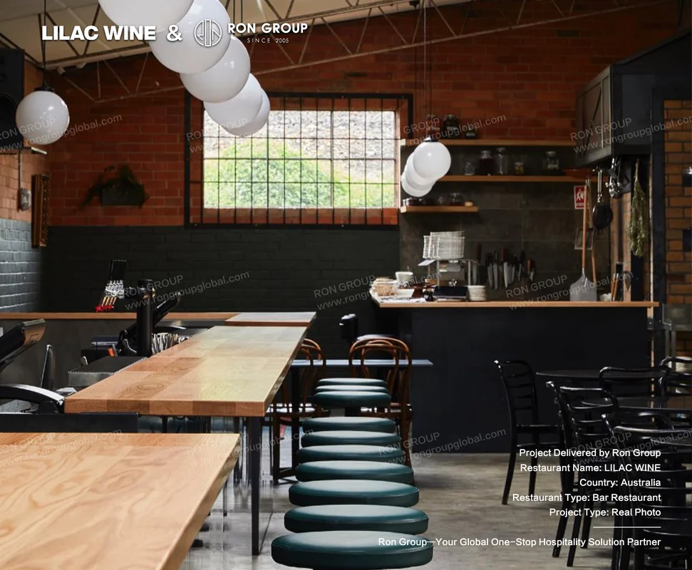 Green cushioned bar stools wooden tables and open kitchen view at Lilac Wine