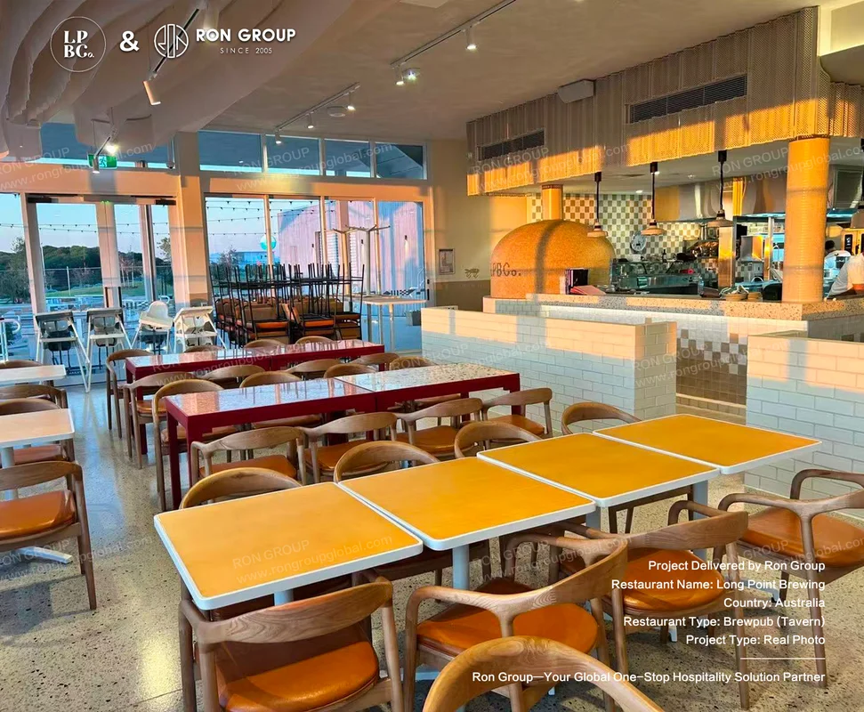 Yellow and red dining tables with wooden chairs beside the orange pizza oven bar