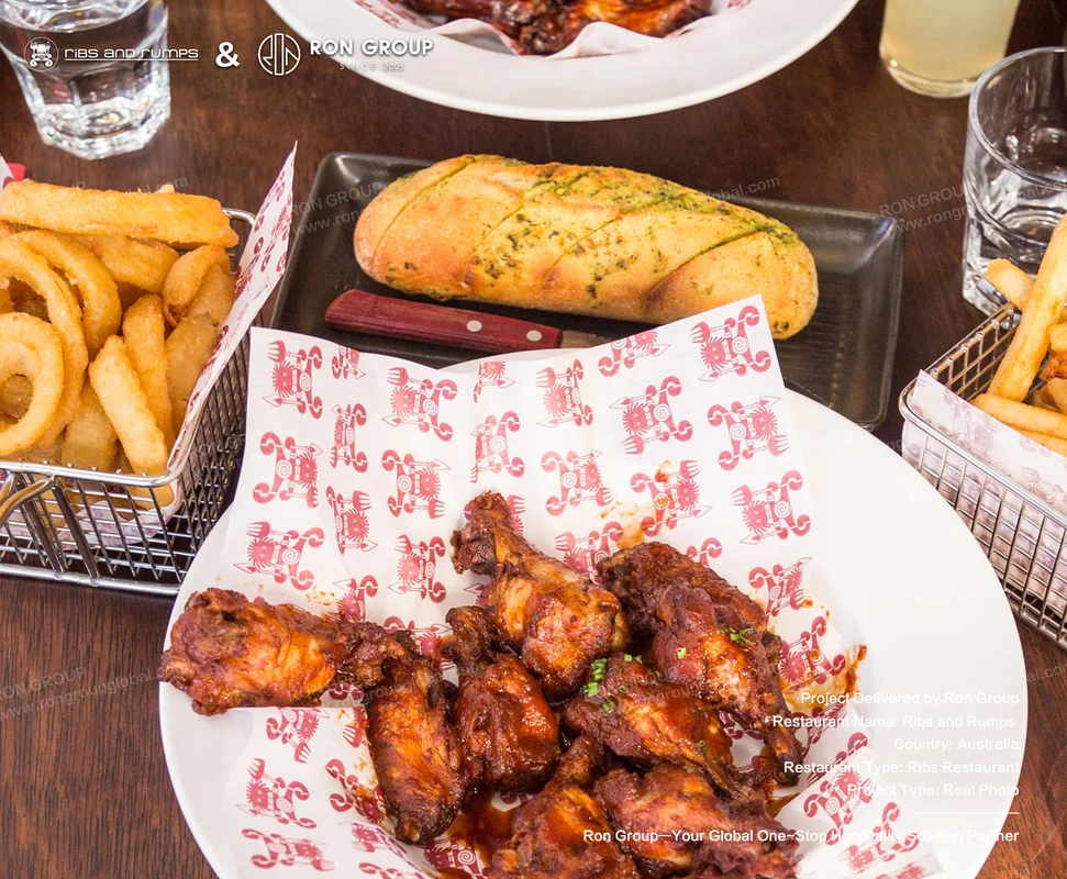 Crispy chicken wings and fries served on branded parchment on a durable commercial table