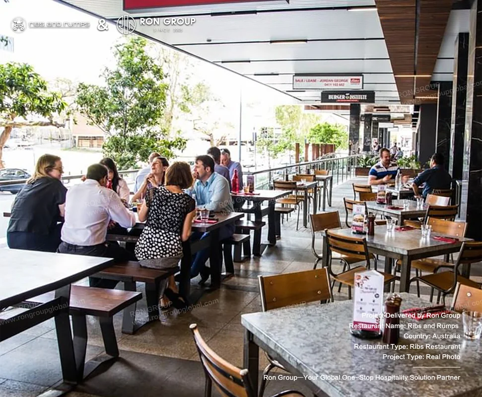 Outdoor dining terrace at Ribs and Rumps featuring industrial wood tables and modern chairs