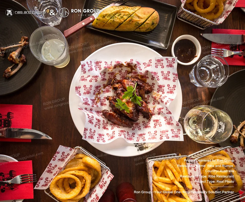 Overhead view of solid timber dining tabletop loaded with appetizers, wings, and branded napkins
