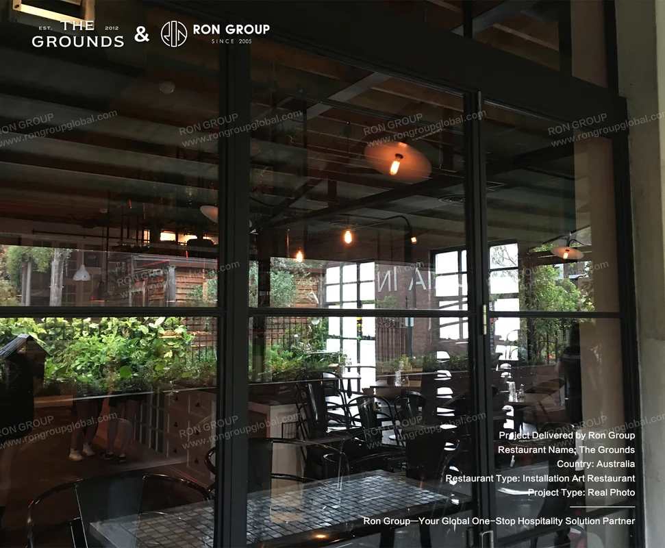 Expansive black-framed glass facade revealing warm timber ceilings and industrial cafe seating at Sydney Garden Restaurant