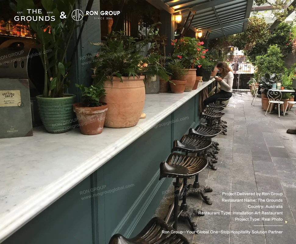 Marble counter bar seating with terracotta potted plants and ornate black metal bar stools at Sydney Garden Restaurant