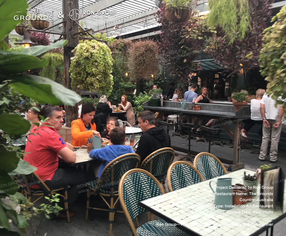 Outdoor dining patio featuring patterned mosaic tables and woven dining chairs surrounded by lush greenery at Sydney Garden Restaurant