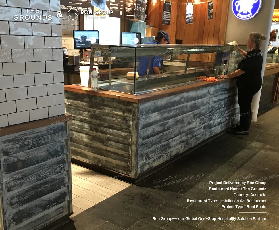 Weathered timber service counter with glass display cabinet and subway tile backdrop at Sydney Garden Restaurant