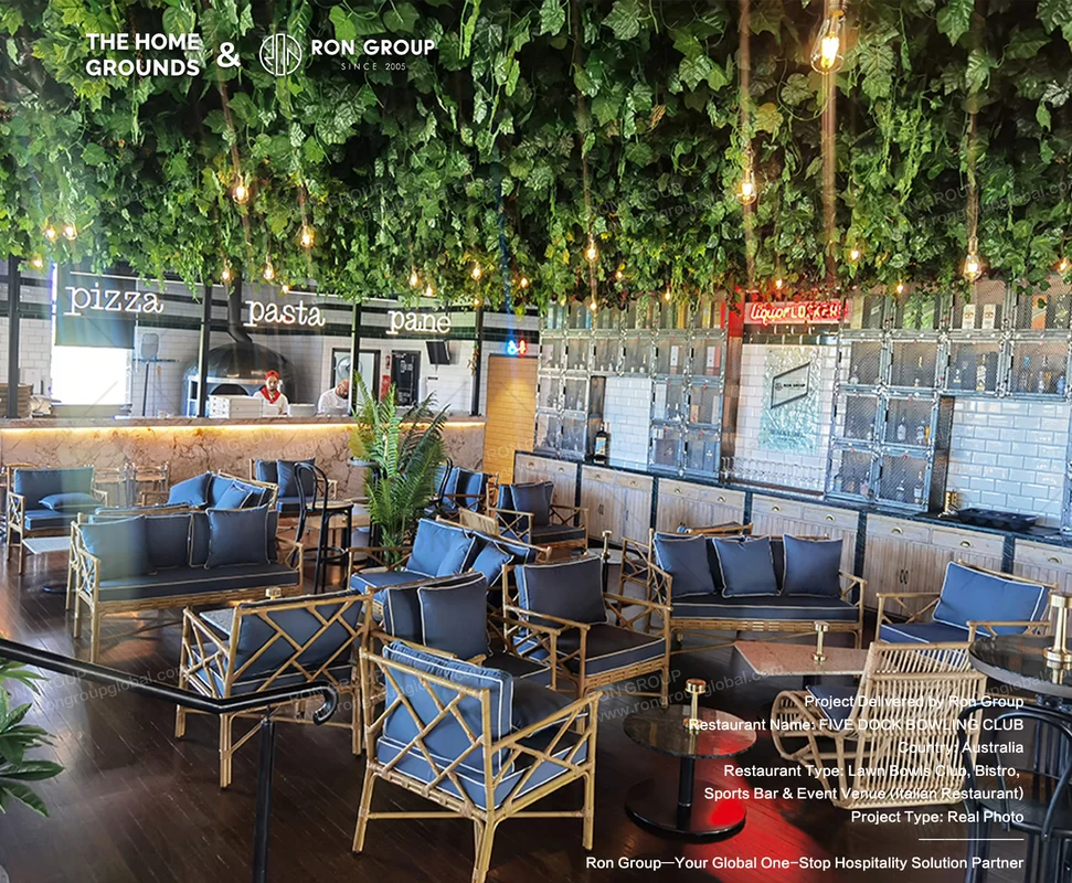Lush green ceiling canopy with Edison bulbs rattan chairs and glass liquor lockers