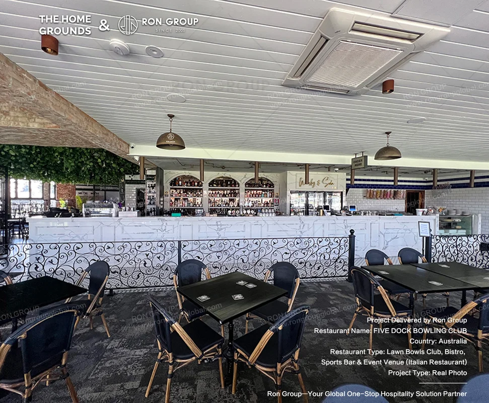 Bistro seating area adjacent to the marble bar and ornate iron railing at The Home Grounds