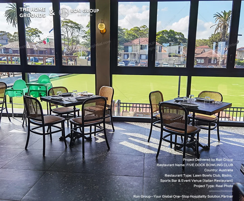 Sunlit veranda dining room with woven chairs overlooking the green bowling lawn