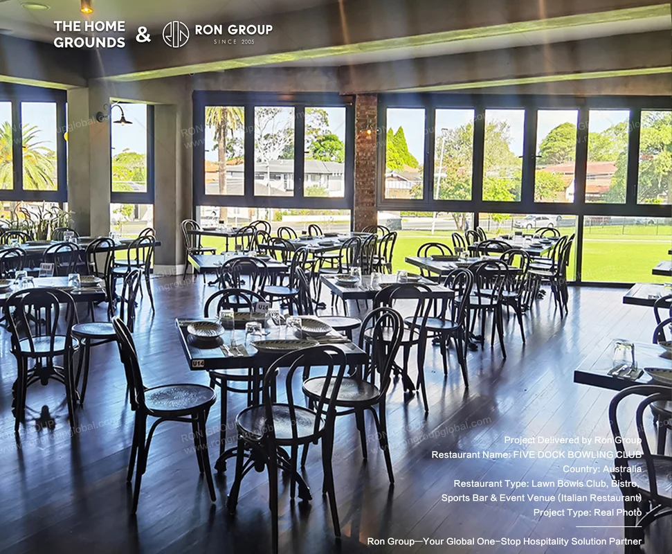 The Home Grounds bright bistro dining hall with black metal tables and park views
