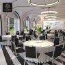 A large room with multiple round tables and black fabric conference chairs.
