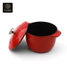A red, pumpkin-shaped enamel cast iron dutch oven with its lid, shown on a wooden surface.