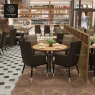 Beige and dark high-back armchairs at a round table in a cafe.