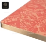 A close-up of a square coral table top with a decorative pattern and a gold edge.