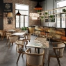 A cafe setting with unique mosaic tables, light wood chairs, and brick walls.